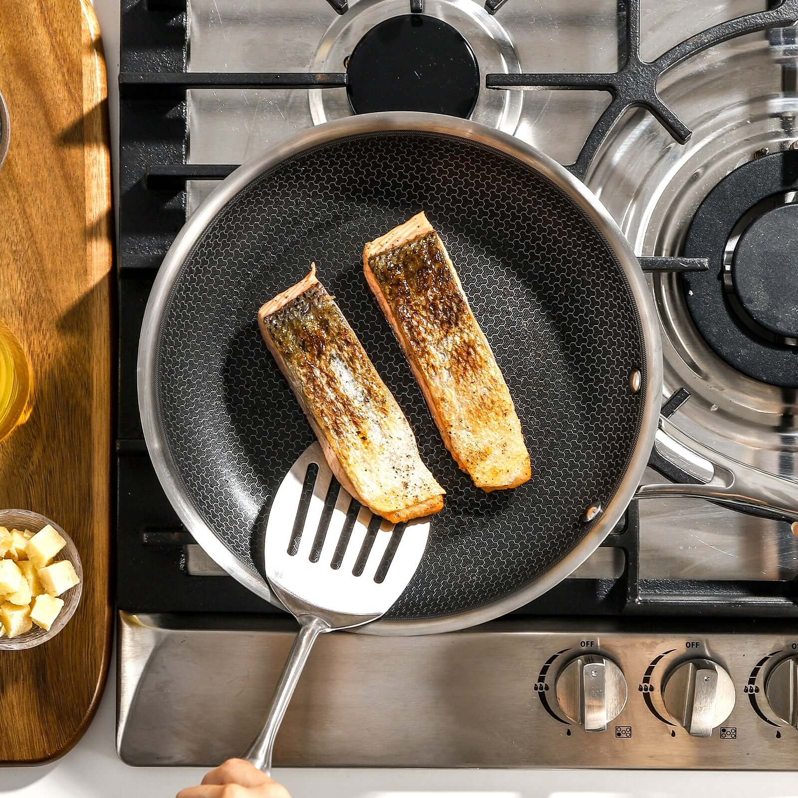 salmon cooking in a hybrid frying pan on a stovetop