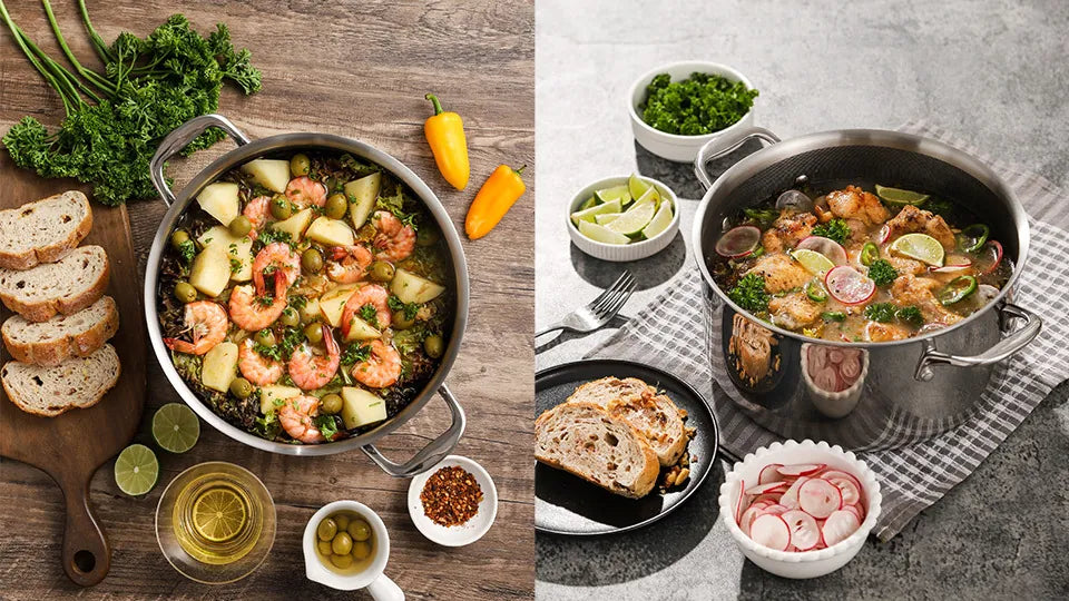 Two stainless steel Dutch ovens filled with braised seafood, chicken, and vegetables next to sliced bread