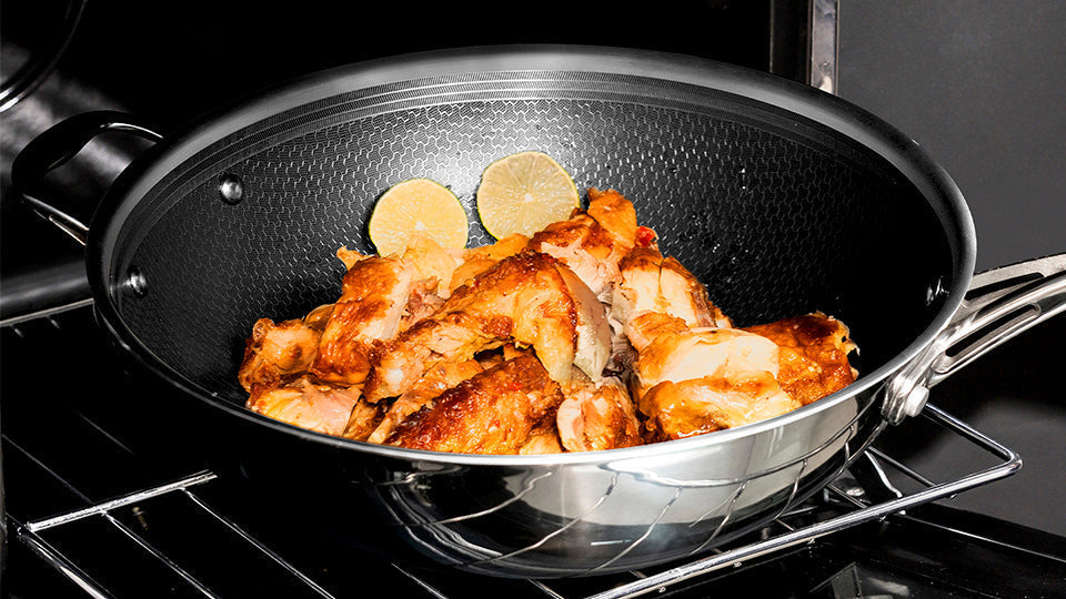 Deluxe Cookware non-stick wok filled with roasted chicken pieces and lime slices on oven rack